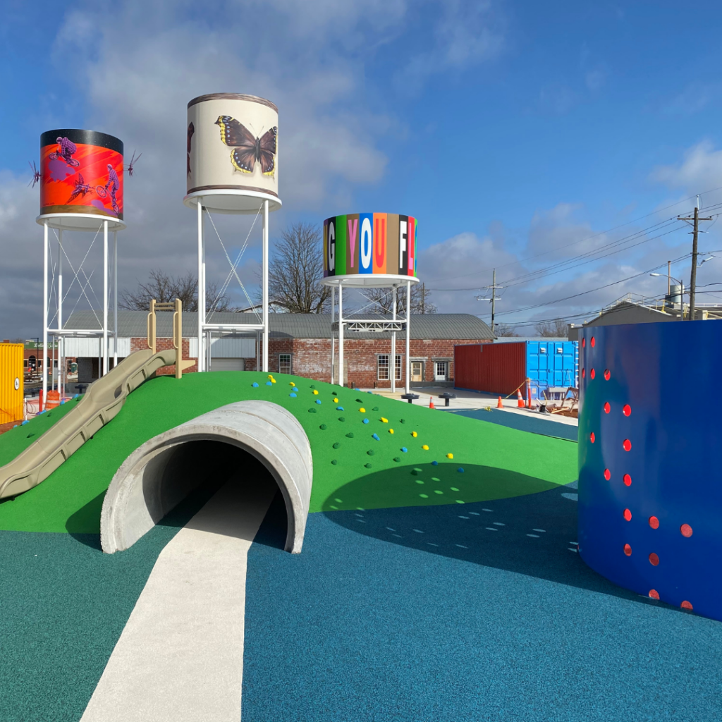 a playground with colorful water towers and a tunnel.