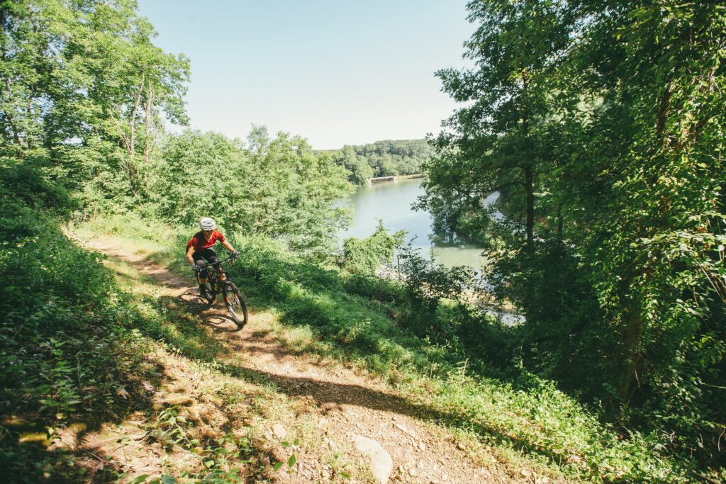 a person riding a mountain bike down a trail near a river.