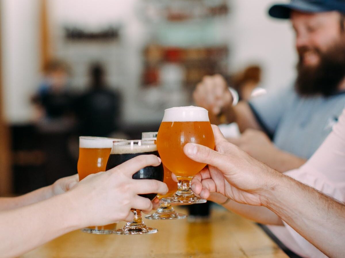 a group of people toasting beer glasses at a bar.